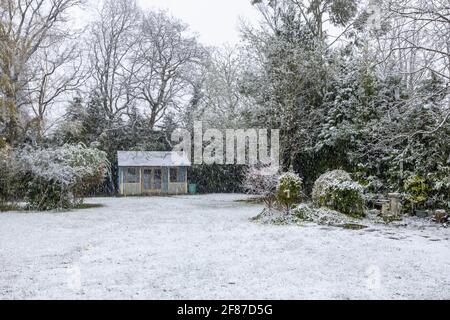 Vue sur un jardin et une maison d'été de banlieue à Surrey, dans le sud-est de l'Angleterre, après une couverture de neige non saisonnière à la mi-avril et de basses températures Banque D'Images