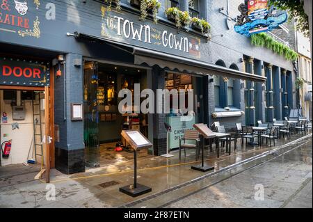 Cambridge, Royaume-Uni. 12 avril 2021. Le personnel nettoie la chaussée et les sièges à l'extérieur de la ville et du pub Gown tandis que les lieux d'accueil rouvrent à Cambridge dans le cadre de l'assouplissement britannique des restrictions de confinement de Covid 19. La feuille de route permet un service extérieur dans les pubs et les bars à partir d'aujourd'hui. Crédit : Julian Eales/Alay Live News Banque D'Images