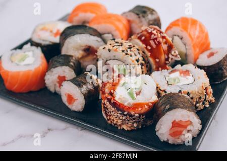 Menu du bar à sushis pour le déjeuner - des petits pains à sushis avec saumon, avocat et anguille smockée sur fond de table en marbre blanc - futomaki, uramaki, maki et hosomaki Banque D'Images