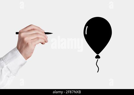 Homme d'affaires avec un stylo dessiner une icône de ballon noir volant. Liberté ou concept commercial indépendant. Banque D'Images