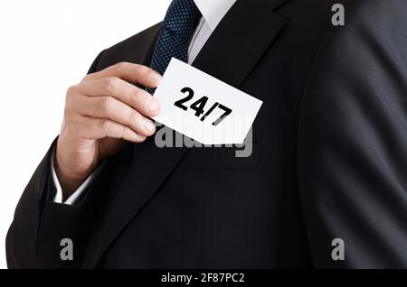 Homme d'affaires sort une carte de sa poche avec le message 24/7. 24 heures 7 jours support, service ou assistance concept. Banque D'Images