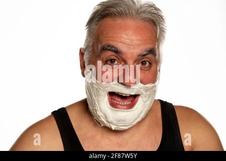 Heureux homme d'âge moyen avec de courts cheveux gris posant avec mousse de rasage sur fond blanc Banque D'Images