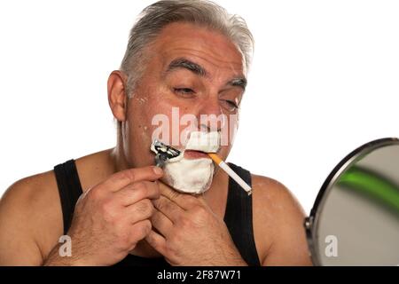 homme d'âge moyen avec cigaret rasse la barbe cachée sur blanc arrière-plan Banque D'Images