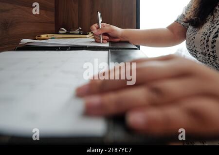 Image en gros plan d'une femme entrepreneur assise à table dans l'hôtel document commercial de la chambre et du remplissage Banque D'Images