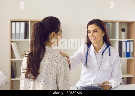 Femme souriante médecin plaçant la main sur l'épaule du patient montrer du soutien à une femme Banque D'Images