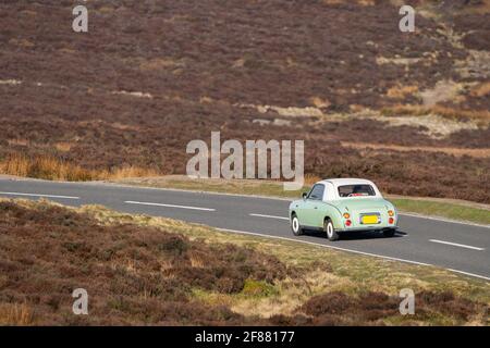 Vieille voiture verte classique conduite seule le long de la route de campagne étroite dans le Derbyshire Peak district campagne moorland le jour ensoleillé. Pittoresque. Banque D'Images
