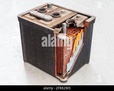 Ancienne batterie de voiture avec corps partiellement ouvert sur une lumière arrière-plan gris Banque D'Images