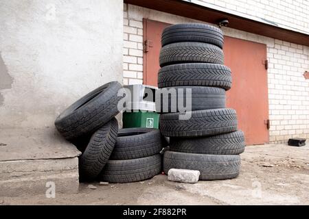 Pile de vieux pneus de voiture contre le mur de brique de service de pneus ou de garage. Pollution, recyclage et réchauffement de la planète. Banque D'Images