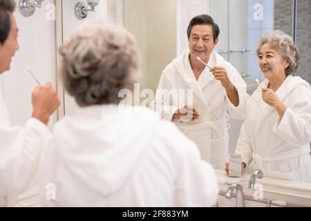 Un couple de personnes âgées heureux se brossant les dents dans la salle de bains Banque D'Images