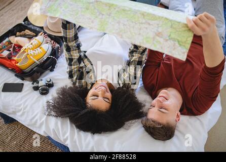 Jeune couple avec carte d'emballage pour les vacances à la maison. Banque D'Images