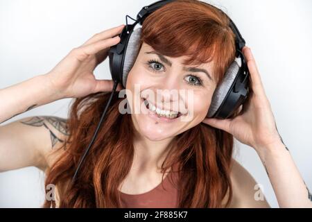 Portrait d'une femme avec des cheveux rouges sur fond blanc porter un casque pour un grand sourire Banque D'Images