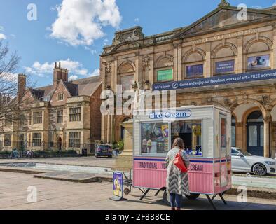 Une galerie d'art à l'architecture de style iItalian est capturée sous un soleil de printemps. Un stand de crème glacée rose et blanche est devant une femme servie Banque D'Images