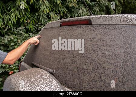 Saint-James, Barbade - avril 11 2021 : un homme écrit sur la lunette arrière d'un véhicule SUV gris recouvert de cendres volcaniques provenant du volcan de la soufrière de Saint-Vincent. Banque D'Images