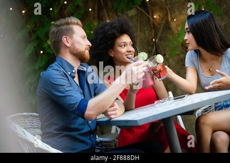 Amis qui se sont bien amusés dans un café, souriant et prenant des cocktails en s'appréciant ensemble. Banque D'Images