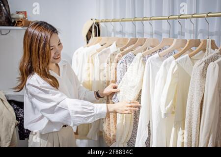 portrait d'une femme entrepreneure asiatique heureuse travaillant dans son magasin moderne avec des vêtements pour femmes, une jeune femme chinoise propriétaire ou consultant tenue Banque D'Images