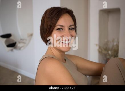 Portrait d'une belle femme de plus de 30 ans, elle sourit avec des dents blanches et regarde dans l'appareil photo. Confiante bonne fille adulte - femme d'affaires dans la chambre Banque D'Images