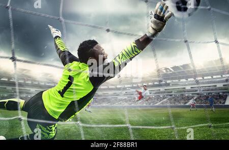 Joueur africain de football ou de football, gardien de but en action au stade. Un jeune homme qui attrape le ballon, s'entraîne, protège les objectifs en mouvement. Banque D'Images