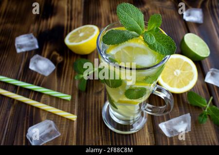 Limonade froide avec citron et menthe dans le verre sur fond de bois brun.gros plan. Banque D'Images