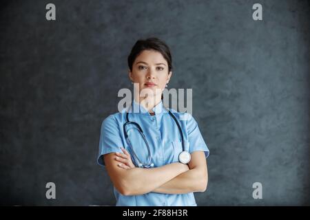 Médecin femme sérieux avec stéthoscope autour du cou debout avec les bras croisés. Elle est médecin dévoué et expérimenté. Banque D'Images