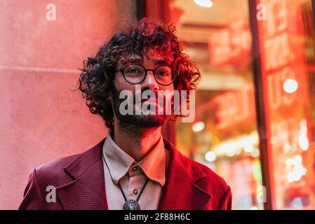 portrait horizontal d'un jeune homme caucasien recevant la lumière néon d'une barre sur son visage. Il s'habille de vêtements et de lunettes tendance Banque D'Images