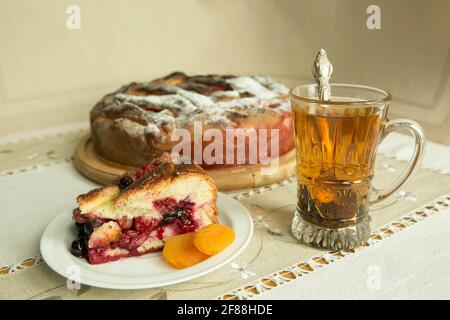 Chaussons de maman. Les chaussons sont prêts. Un morceau de gâteau sur une assiette sur le fond d'une tarte cuite et une tasse avec thé noir. Cuisson en quarantaine. Banque D'Images