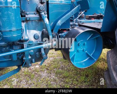 Vue partielle d'un tracteur ancien et restauré en bleu avec vue de la transmission par courroie d'une courroie de transmission et de la tringlerie de direction et d'accouplement. Banque D'Images