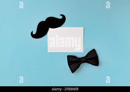 joyeux fête des pères, composition de la moustache noire, noeud papillon et enveloppe sur fond bleu, carte de vœux avec feuille de papier blanche et place pour le tex Banque D'Images