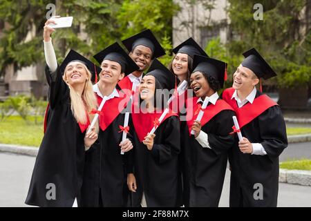 Des diplômés heureux qui se rassemblent sur le campus universitaire Banque D'Images