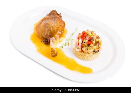 La jambe de canard confite avec du couscous et des légumes cuits au four. Isolé sur un fond blanc. Banque D'Images