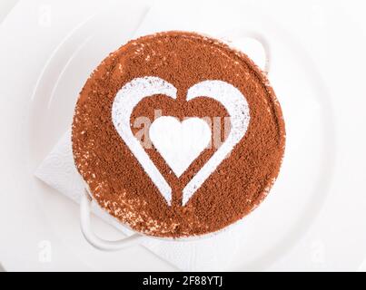 Dessert tiramisu avec motif en forme de coeur de sucre en poudre et garni de chocolat. Macro. La photo peut être utilisée comme arrière-plan entier. Banque D'Images