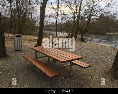 Aire de pique-nique publique vide avec table, bancs et poubelle pour déchets à la fin de l'hiver près de la rivière Aare à Brugg, en Suisse. Banque D'Images