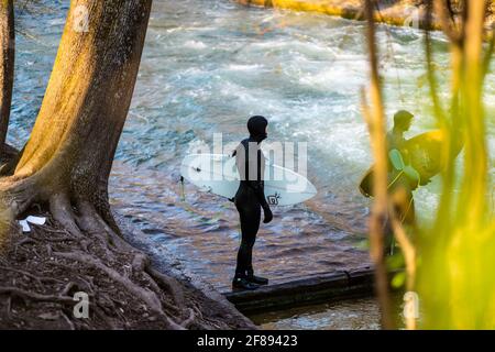 MUNICH, ALLEMAGNE - 10 avril 2021 : surfeurs sur le fameux Eisbachschwelle de Munich, une vague artificielle dans le parc central sur lequel vous pouvez surfer. Banque D'Images