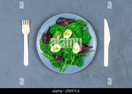 Bol à lunch de feuilles de laitue avec œufs, fourchette en bois et cuillère sur fond gris. Concept d'alimentation saine. PP. Vue de dessus. Aucun gaspillage. Banque D'Images