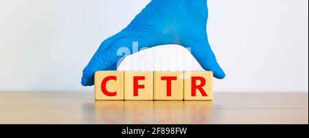 Symbole CFTR. Cubes en bois avec les mots « CFTR - régulateur transmembranaire de fibrose kystique », main médecin dans un gant bleu. Magnifique fond blanc. Médical, Banque D'Images