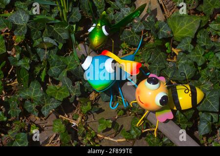 Statuettes étain insectes assis sur un bâton de bois dans le jardin Banque D'Images