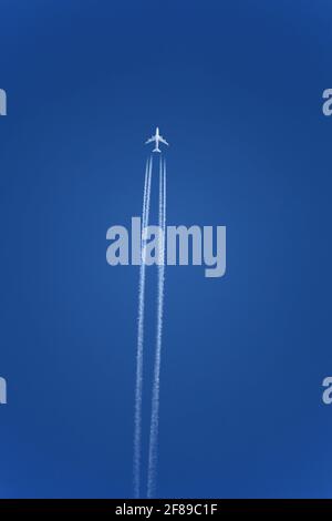 Avion avec contrailles dans un ciel bleu clair, altitude de croisière. Les jets laissent des sentiers blancs, ou contrails, dans leurs éveils pour la même raison que vous pouvez quelque chose Banque D'Images