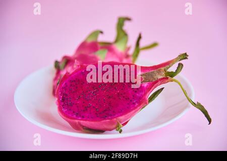 Assiette de fruits exotiques Dragon pitaya. Nutrition fruits asiatiques mûrs crus délicieux. Pitahaya coupé en 2 moitiés sur fond rose Banque D'Images