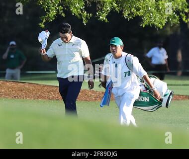 Augusta, États-Unis. 11 avril 2021. Hideki Matsuyama pointe sa casquette en se promenant vers le 18ème green avec son caddie Shota Hayafuji sur son chemin pour gagner les maîtres le dimanche 11 avril 2021, au club de golf national d'août à Augusta, Géorgie. (Photo de Curtis Compton/Atlanta Journal-Constitution/TNS/Sipa USA) crédit: SIPA USA/Alay Live News Banque D'Images