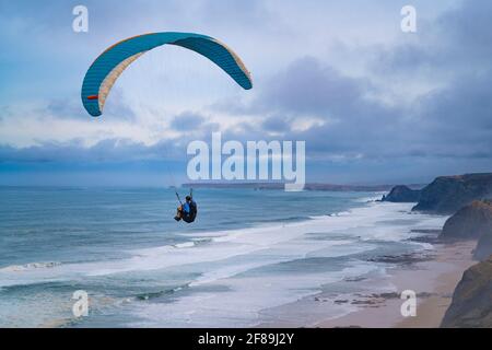 Vila do Bispo, Portugal - 12 février 2020 : un parapente survolant les falaises pittoresques de la plage de Cordoama (Praia da Cordoama) près du village de Banque D'Images