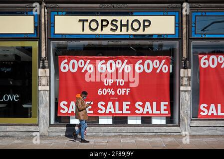 Homme regardant son téléphone alors qu'il passe devant le panneau Vente sur le magasin Topshop maintenant fermé sur Princes Street, Edimbourg, Ecosse, Royaume-Uni. Banque D'Images