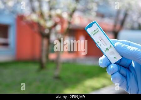 Les mains tient un test rapide à l'extérieur, avec un bureau, une école ou un jardin d'enfants hors de portée. Express COVID19 test, Schnelltest est rapide corona test in Banque D'Images