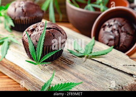 Cuisson des muffins aux mauvaises herbes au chocolat. Cupcake avec marijuana sur table en bois. Muffins au chocolat avec de l'herbe de cannabis cbd. Marijuana médicale Banque D'Images