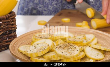 Tranches de courgettes sur une assiette, assaisonnement au sel d'ail et poivre frais moulu. Courgettes cuites au four avec fromage et recette d'épices Banque D'Images