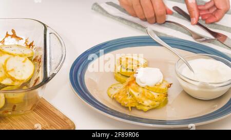 Courgettes cuites sur une assiette. Tranches de courgettes avec sel d'assaisonnement, poivre noir et fromage, servies avec de la crème aigre. Banque D'Images