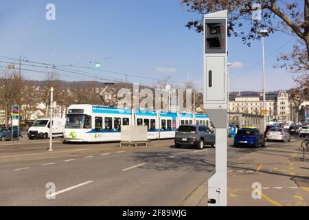 Zurich, Suisse - 10 mars 2021 : circulation routière en soirée : radar de vitesse et de lumière rouge dans un seul appareil, tramway blanc en arrière-plan, par jour Banque D'Images