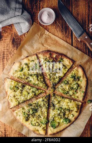 Pizza maison en tranches avec brocoli, sauce pesto, herbes et fromage sur papier de cuisson. Vue de dessus Banque D'Images