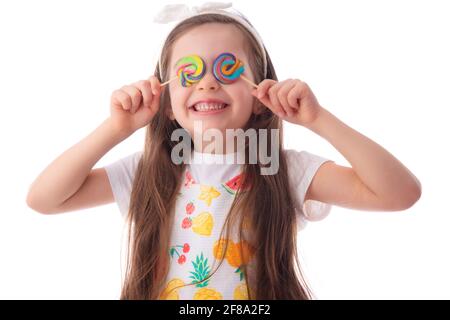 Petit enfant mangeant du sucettes. Bonne fille belle avec des bonbons isolés sur fond blanc. Banque D'Images