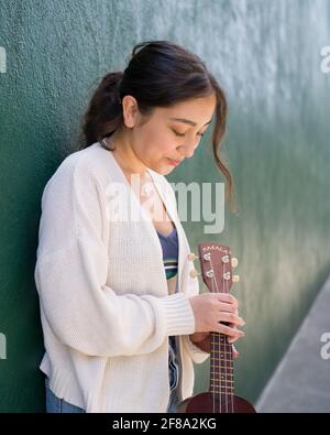 Petite adolescente asiatique debout avec ukulele Banque D'Images