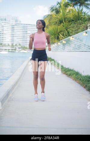Portrait d'une jeune femme afro-américaine qui fait du jogging et de la marche dehors le long de l'eau Banque D'Images
