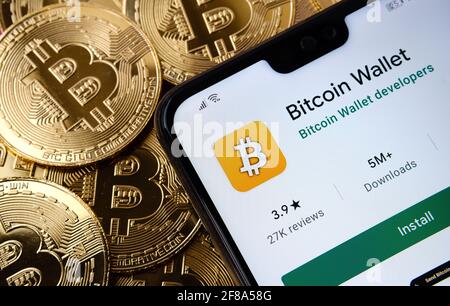 Application Bitcoin Wallet vue sur l'écran du smartphone placé sur la pile de bitcoin supérieure. Concept. Stafford, Royaume-Uni, 12 avril 2021. Banque D'Images